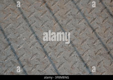 Galvanized checkered steel diamond plate metal floor texture with diagonal shadow lines. Stock Photo