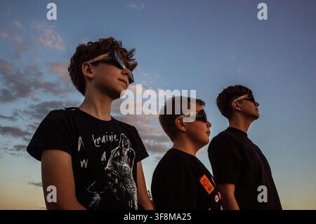 Three boys seen looking at the solar eclipse through filtered spectacles. On the evening of the 12th August, Prime Minister of the Republic of Poland, Donald Tusk, joins scientific observers and members of the public at the Copernicus Science Centre in Warsaw to watch a partial solar eclipse. At its maximum, the Moon obscures about 82% of the Sun as viewed from the Polish capital. Warsaw's eclipse runs from approximately 19:14 until sunset at 20:06, reaching its maximum at 20:02. The roughly 82% figure refers to the Sun's covered area; the eclipse magnitude was about 0.85. Stock Photo