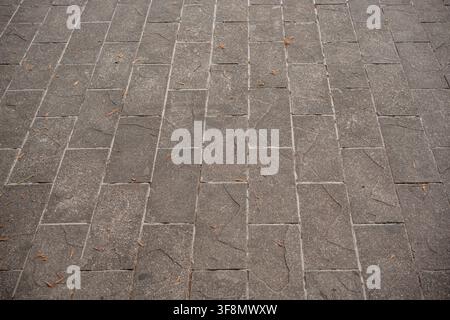 Perspective view of a grey stone paved walkway with rectangular paving slabs. Stock Photo