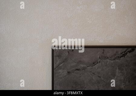 Minimalist architectural detail of a dark marble corner against a textured beige plaster wall. Stock Photo