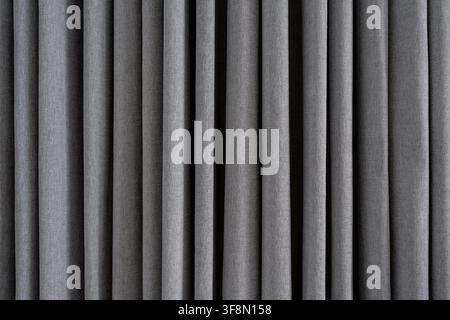 Grey textured fabric curtain background with deep vertical folds. Stock Photo