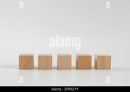 Five blank wooden cubes aligned in a row on a white background, suitable for business planning, workflow, sequence, organization, education, mockup, s Stock Photo