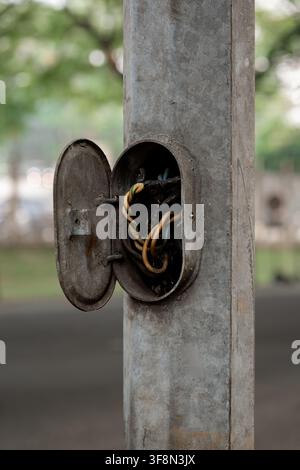 Open electrical access panel on a metal street light pole exposing twisted wires. Stock Photo