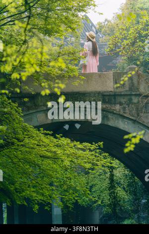 Woman with straw hat and umbrella on old stone bridge, Liulang Wenying, Hangzhou Stock Photo