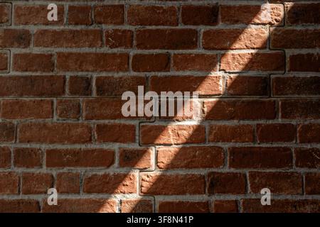 Red brick wall texture with a distinct diagonal shadow cast across. Stock Photo