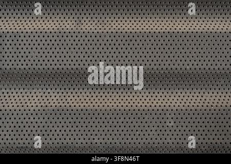 Dark grey perforated metal sheet texture with repeating circular holes. Stock Photo
