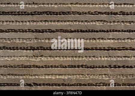Textured brown stone wall cladding with horizontal chiseled ribbed pattern background. Stock Photo
