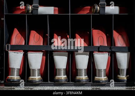 Rolled red fire hoses stored in the compartment of a fire engine. Stock Photo
