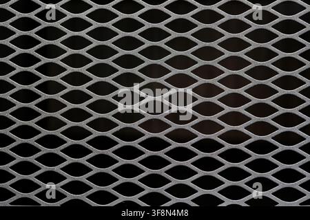 Expanded metal mesh grating with diamond pattern over dark background. Stock Photo