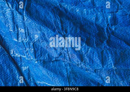 Close up background texture of a wrinkled blue plastic tarp with a woven pattern. Stock Photo