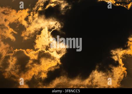 Golden sunlight breaking through dramatic dark clouds in the sky Stock Photo