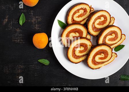 Traditional Swiss Roll with Apricot Filling and Fresh Apricots. Top view Stock Photo