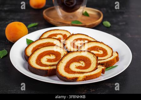 Homemade Apricot Swiss Roll Cake Sliced on White Plate Stock Photo