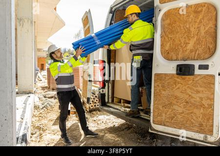 Professional builders moving blue plastic pipeline elements Stock Photo