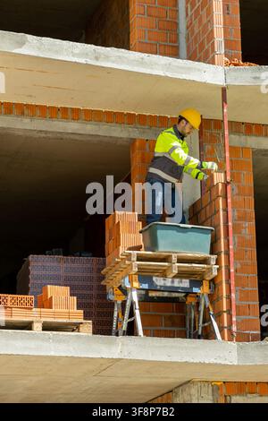 Close up of focused bricklayer building red brick wall Stock Photo