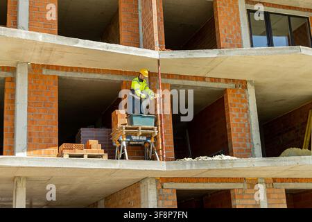 Professional mason holding spirit level tool on red brick wall Stock Photo