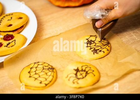 Close up view of the decorating process of festive Halloween biscuits with spooky facial features Stock Photo