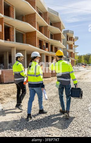 Group of engineers walking on gravel path gesturing and discussing Stock Photo