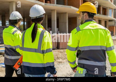 Close up of three builders in helmets looking at structure Stock Photo