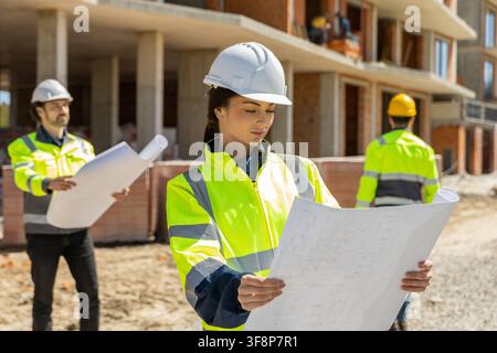 Female lead architect examining paper blueprint Stock Photo