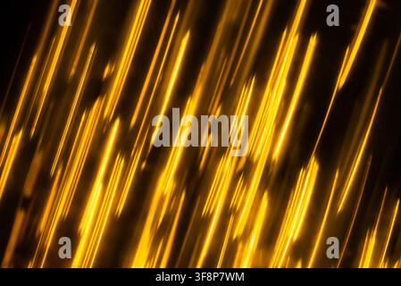 Shining yellow stripes and warm lens flare streaks moving smoothly across a dark background Stock Photo