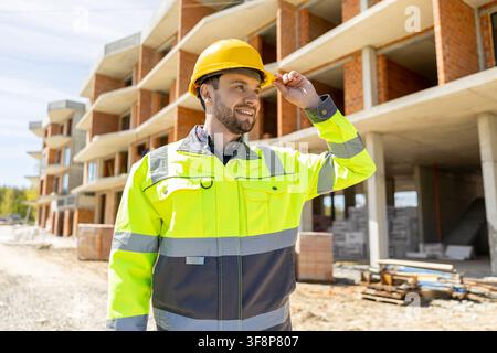 Confident construction supervisor adjusting yellow helmet Stock Photo