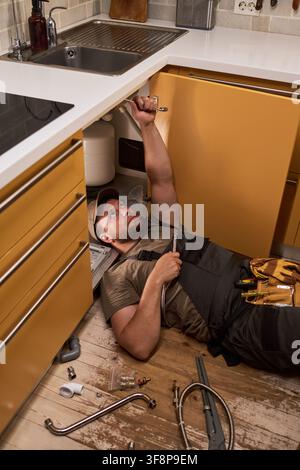Plumber Repairing Kitchen Sink Pipe in Home Maintenance Service Stock Photo
