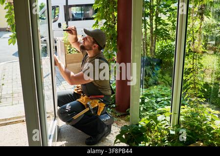 Man Repairing Glass Door Lock with Screwdriver Stock Photo