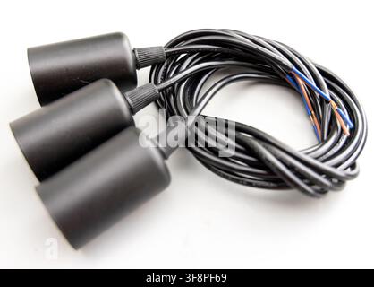 Three black lamp holders are connected to coiled electrical wire Stock Photo