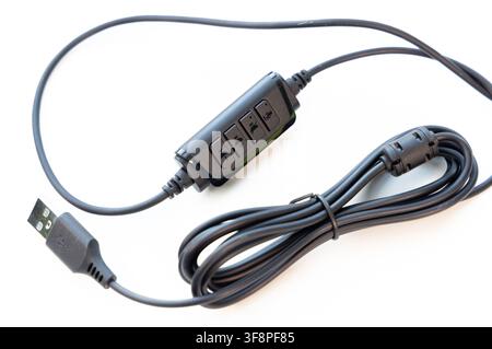 A black USB cable with inline audio controls rests on a white background Stock Photo