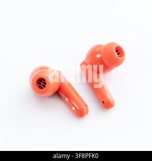 Two vibrant orange wireless earbuds are displayed on a clean white background Stock Photo