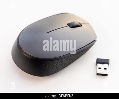 A black wireless computer mouse and its USB receiver sit on white Stock Photo