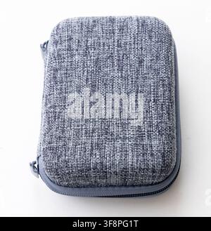 A gray fabric zippered hard case rests on a white surface Stock Photo