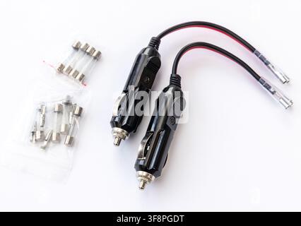 Two car cigarette lighter plugs and fuses are shown on a white background Stock Photo