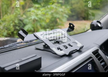A car dashboard tablet holder mounted on vehicle dash with adjustable metal cradle holding tablet securely for hands free navigation and entertainment Stock Photo