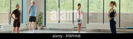 Diverse group of senior and mature Caucasian people practicing yoga with young female instructor in gym. Image suitable for active aging and senior wellness marketing campaigns Stock Photo