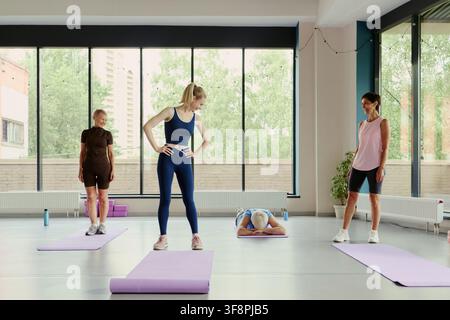 Diverse Caucasian women of different ages practicing yoga in modern studio, young female instructor guiding senior students, promoting active aging and wellness, wide shot Stock Photo