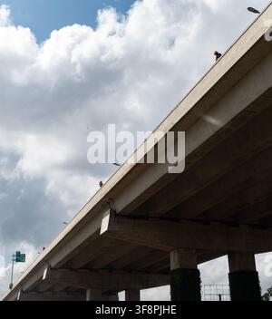 Nairobi, Kenya - 02 April 2022: View of a concrete highway overpass with construction workers wearing yellow helmets standing on the edge under a clou Stock Photo