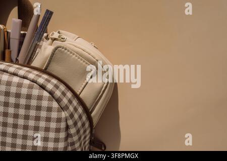 Checkered backpack with stationery and pencil case in warm light, back to school background Stock Photo