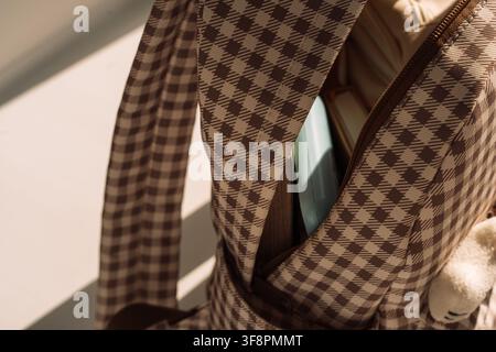 Open checkered backpack with school supplies in dramatic sunlight, back to school concept Stock Photo