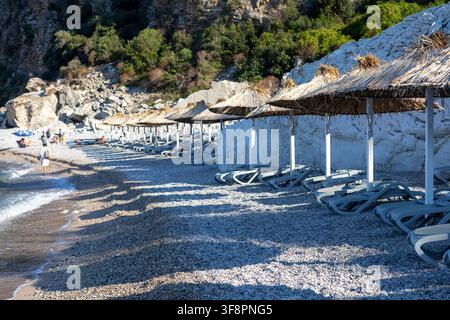 a tranquil beach scene featuring rocky cliffs and white umbrellas, set against a backdrop of a calm coastal landscape, evoking a sense of relaxation a Stock Photo