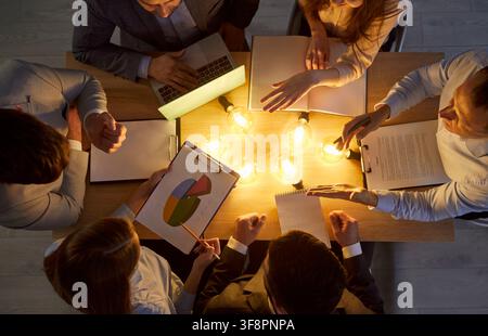 Coworkers Working With Light Bulbs In Office Stock Photo