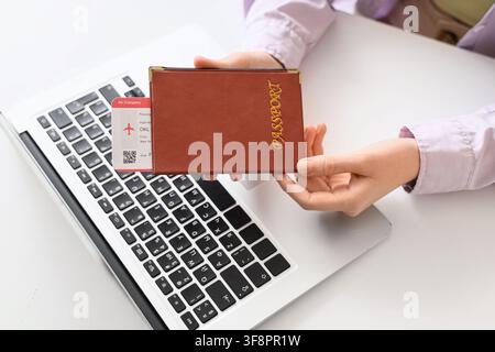 Person holding a passport and airline ticket over a laptop keyboard online travel booking and international journey, this image online travel booking Stock Photo