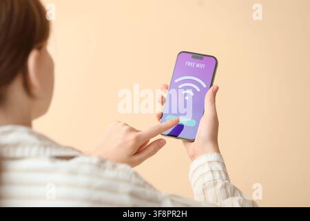 Person connecting to free wifi network on a smartphone, wireless internet access and digital communication concept, a person is shown from behind Stock Photo