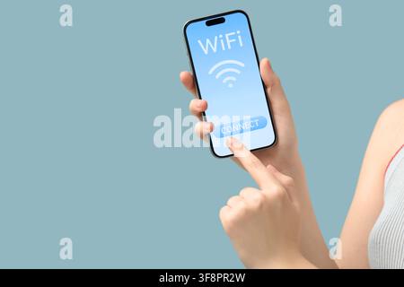 Womans hand holding a smartphone with a wifi connect button on the screen internet access and wireless technology Stock Photo