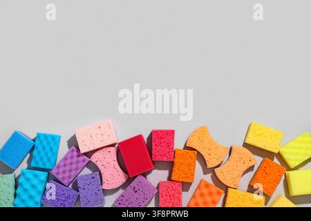Colorful cleaning sponges in various shapes and sizes arranged in a rainbow pattern on a light gray background, the flat lay composition offers ample Stock Photo