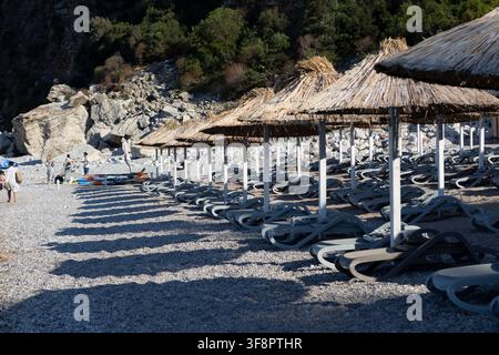a tranquil beach scene featuring rocky cliffs and white umbrellas, set against a backdrop of a calm coastal landscape, evoking a sense of relaxation a Stock Photo