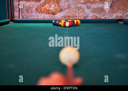 Hand placing cue ball on a green billiard table, colorful balls racked in triangle Stock Photo