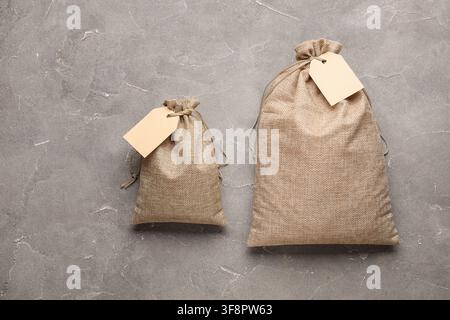Full sacks with tags on grunge grey background Stock Photo