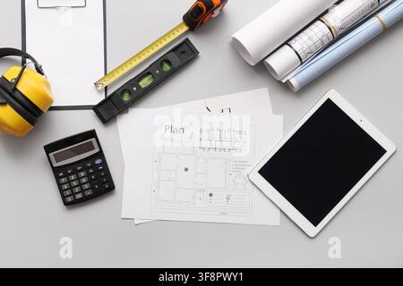 Construction planning and architectural design tools with blueprints, calculator, and digital tablet on a gray background Stock Photo
